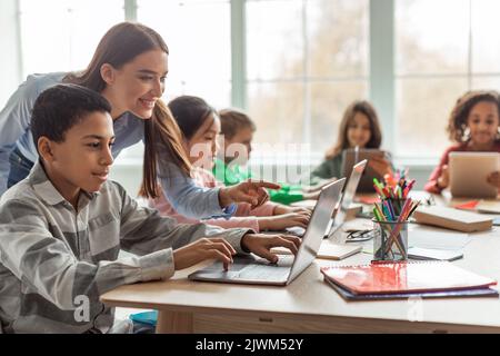 Lehrer Unterrichten Verschiedener Schüler Mit Laptop Im Klassenzimmer Stockfoto