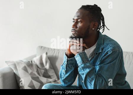 Ernster Afroamerikanischer Mann, Der Zu Hause Sitzt, Seitenansicht Stockfoto