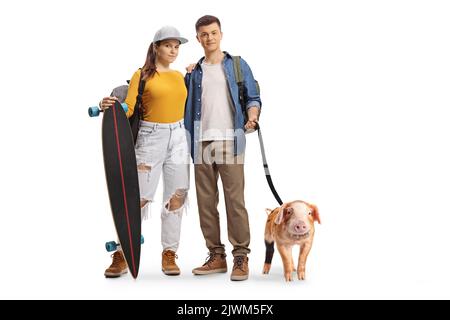 Teenager Mädchen und Kerl mit einem Longboard und einem Schweinchen Haustier auf einem Blei isoliert auf weißem Hintergrund Stockfoto