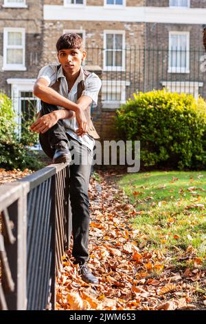 Teenager: Sitzen auf dem Zaun. Ein freundlicher Teenager in entspannter Stimmung. Aus einer Reihe von Bildern von Schülern. Stockfoto