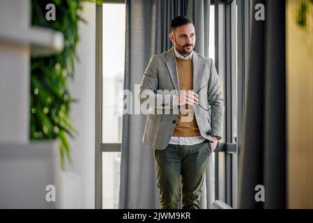 Eleganter Unternehmer Geschäftsmann, einen Spaziergang durch sein Büro, trägt seine Brille, stilvoll. Stockfoto