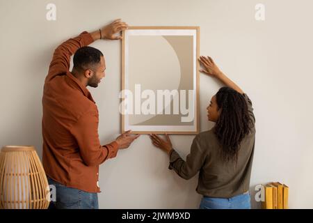 Afroamerikanisches Paar Hängende Poster An Der Wand Zu Hause Stockfoto
