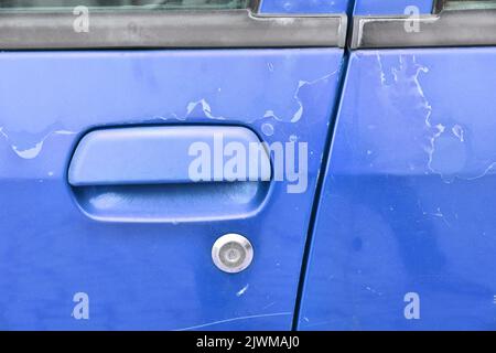 Veraltete Autofarbe - abblätternde Lackoberfläche in einem 20 Jahre alten europäischen roten Auto. Stockfoto