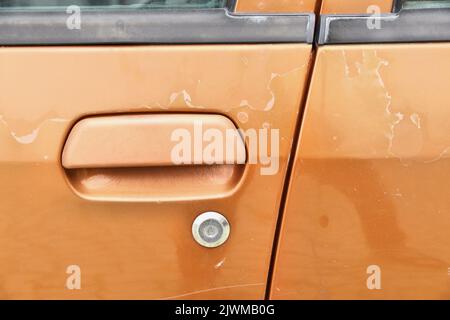 Verwitterte Fahrzeugfarbe - alternde abblätternde Fahrzeuglackoberfläche. Sonneneinstrahlung beschädigt. Stockfoto