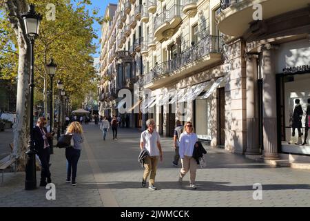 BARCELONA, SPANIEN - 7. OKTOBER 2021: Besucher besuchen die Straße Passeig de Gracia im Stadtteil Eixample, Barcelona, Spanien. Passeig de Gracia ist berühmt für seine Stockfoto