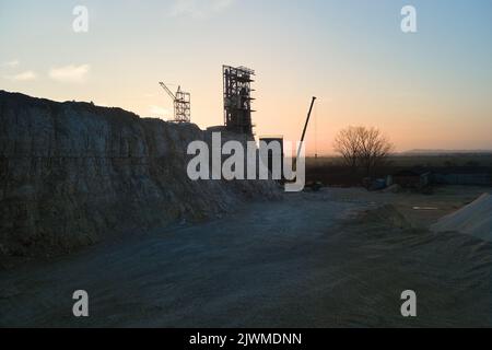 Zementfabrik im Tagebau für Bau-Sandsteinmaterialien. Graben von Kiesvorkommen im Steinbruch bei Sonnenuntergang Stockfoto