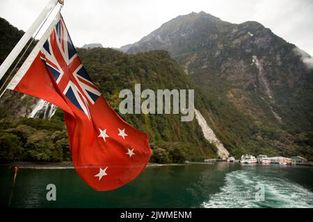 Neuseeländische Flagge winkt im Milford Sound in Neuseeland Stockfoto