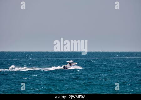 Meereslandschaft mit Wellenoberfläche aus blauem Meerwasser mit weißem Schnellboot, das schnell auf ruhigen Wellen schwimmt Stockfoto