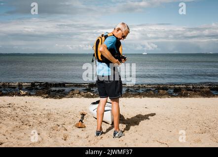 Pensionierter Mann, der mit seinem Kajak auf dem Meer trainieren wollte Stockfoto