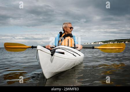 Rentner trainieren im Meer auf einem Kajak an der Jurassic Coast Stockfoto