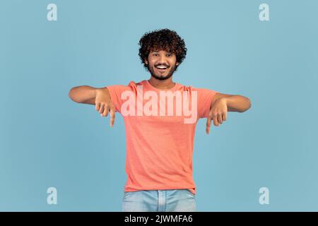 Glücklicher indischer Mann zeigt nach unten und lächelt Stockfoto