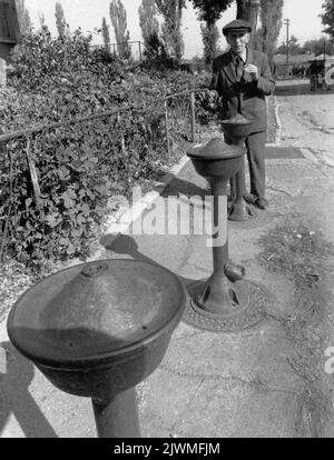 Bukarest, Rumänien, 1990. Mann vor einem Brunnen auf der Straße. Stockfoto