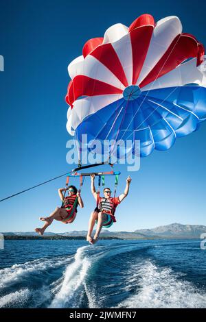 Ein Mann und eine Frau genießen einen klaren Sommermorgen des Parasailings. Stockfoto