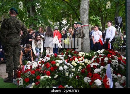 06. September 2022, Brandenburg, Fürstenberg/Havel: Junge Menschen legen Blumen und Kränze bei der Beerdigung der Überreste polnischer Gefangener des Konzentrationslagers Ravensbrück auf dem Friedhof ab. Die Asche der KZ-Opfer war 2019 bei Suchgrabungen des Polnischen Instituts für nationales Gedenken (IPN) auf dem Fürstenberg-Friedhof geborgen worden. Am ersten Tag der Untersuchung wurden Urnen mit Asche und Überresten von ermordeten polnischen Frauen gefunden. Ebenfalls erhalten waren Aluminiumbleche und Feuerstein, auf die die Daten der Opfer gestempelt wurden. Stockfoto