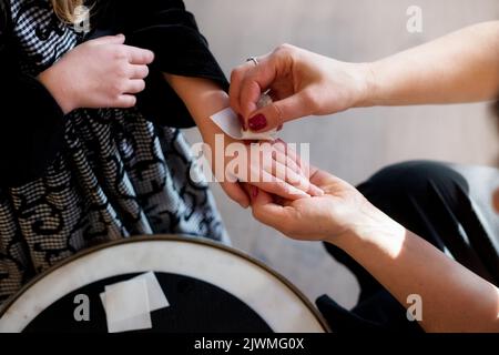 Eine Frau klebt eine Zeichnung auf die Hand eines Mädchens Stockfoto