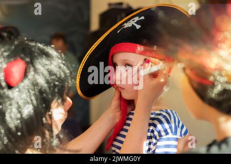 Der Animator zieht an halloween Spinnweben auf das Gesicht des Jungen Stockfoto