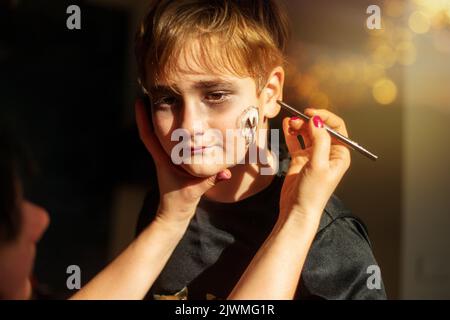 Der Animator zieht an halloween Spinnweben auf das Gesicht des Jungen Stockfoto