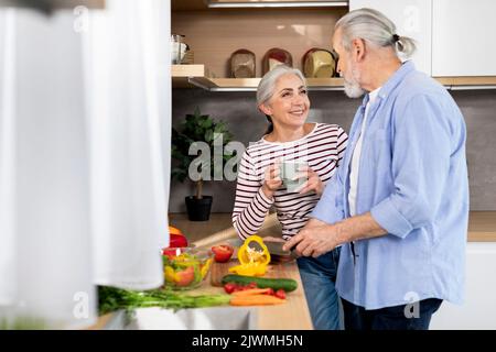 Portrait eines schönen älteren Paares, das zu Hause in der Küche das Mittagessen zubereitet Stockfoto