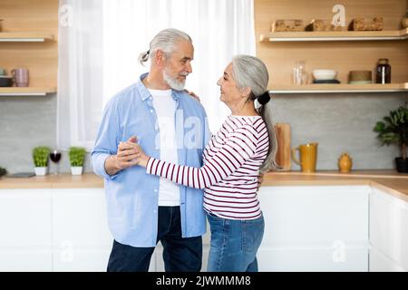 Porträt Eines Romantischen Älteren Ehepaars, Das Gemeinsam In Der Küche Tanzt Stockfoto