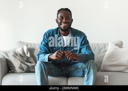 Happy Black Man Posiert Auf Der Couch Zu Hause Sitzen Stockfoto