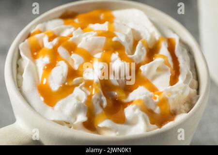 Warmes Caramel-Latte-Getränk in einer Tasse mit Schlagsahne Stockfoto