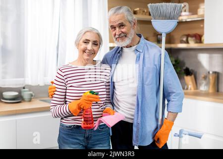 Hausarbeit Konzept. Glückliche Ältere Ehepartner Posieren Mit Reinigungsmitteln In Der Küche Stockfoto