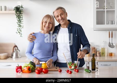 Attraktive ältere Männer und Frauen, die zu Hause zusammen kochen Stockfoto