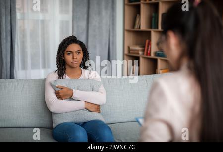 Beratung mit Psychologen. Verzweifelte junge afroamerikanische Frau, die kaukasische Ärztin im Büro ansieht Stockfoto