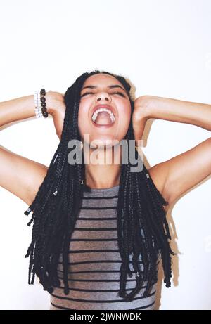 Zu viel Lärm. Studioaufnahme einer attraktiven jungen Frau, die ihre Ohren bedeckt. Stockfoto