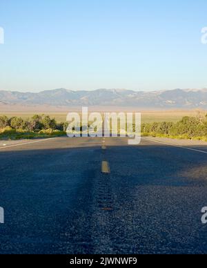 Endlose Wüstenautobahn, die in die Berge führt Stockfoto