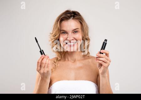 Konzept Erstellen. Porträt Einer Lächelnden Dame Mittleren Alters, Die Die Geöffnete Mascara Vorführt Stockfoto