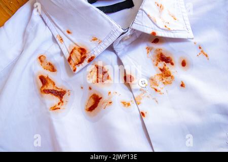 Lebensmittelflecken auf dem Hemd. Draufsicht Tomatensauce Schmutz auf weißem Hemd. Stockfoto