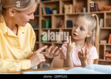 Hübsches kleines Mädchen, das im Büro des privaten Lehrers auf die Finger zählt, das Kind, das die Zahlen lernt und wie man zählt Stockfoto