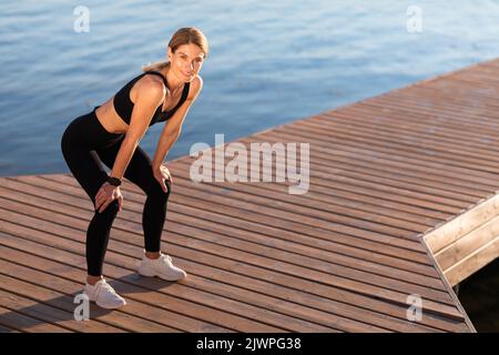 Sportliche Frau, Die Beim Training Im Freien Eine Pause Macht, Hände Auf Den Knien Auslegend Stockfoto