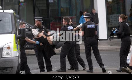 Newquay, Cornwall, Großbritannien. 06. September 2022. Eine umstrittene Spit-Maske, die auf einer Person verwendet wird, die von Polizisten aus Devon und Cornwall auf der Polizeistation Newquay festgenommen wurde. Der Vorfall ereignete sich um 16:06 Uhr an der vielbefahrenen Kreuzung von Oakleigh Terrace und Cliff Road Newquay. Die Person wurde von sechs Beamten an die Straße geklemmt und daraufhin in einen Polizeiwagen gehoben. Die Polizei von Devon und Cornwall benutzte letztes Jahr zweimal Spuhhauben oder Beißschutz bei Kindern unter elf Jahren. Kredit: Robert Taylor/Alamy Live Nachrichten Stockfoto