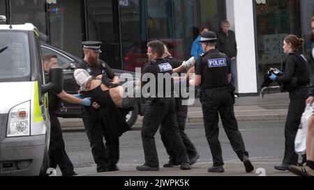 Newquay, Cornwall, Großbritannien. 06. September 2022. Eine umstrittene Spit-Maske, die auf einer Person verwendet wird, die von Polizisten aus Devon und Cornwall auf der Polizeistation Newquay festgenommen wurde. Der Vorfall ereignete sich um 16:06 Uhr an der vielbefahrenen Kreuzung von Oakleigh Terrace und Cliff Road Newquay. Die Person wurde von sechs Beamten an die Straße geklemmt und daraufhin in einen Polizeiwagen gehoben. Die Polizei von Devon und Cornwall benutzte letztes Jahr zweimal Spuhhauben oder Beißschutz bei Kindern unter elf Jahren. Kredit: Robert Taylor/Alamy Live Nachrichten Stockfoto