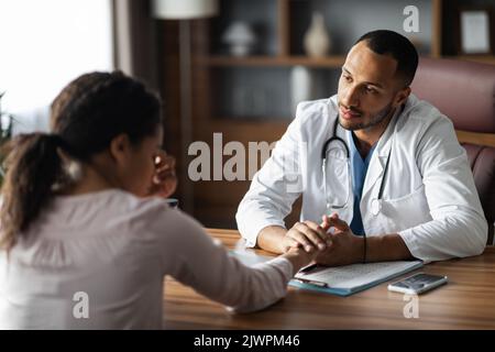 Arabischer Mann Arzt mit Gespräch mit verärgert schwarze Frau Patientin Stockfoto