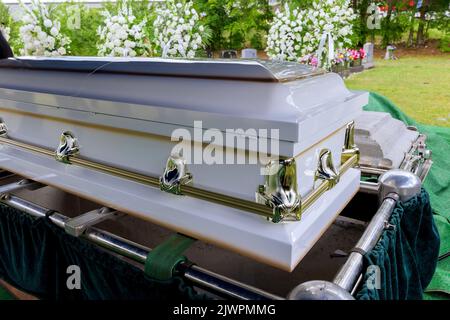 Trauerdienst auf dem Friedhof mit Sarg auf dem Aufzugssystem des automatischen Sinkens in das Grab Stockfoto