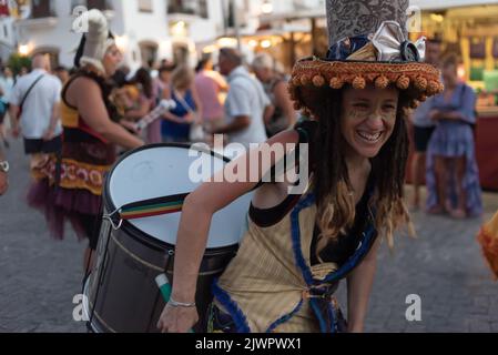 Frigiliana, Malaga, Spanien, 27. August 2022: batucada-Straßenkünstler mit großer Trommel und großem Zylinderhut mit baumelnden Quasten Stockfoto