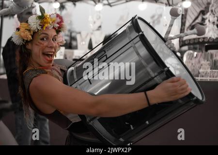 Frigiliana, Malaga, Spanien, 27. August 2022: Straßenkünstler, Verkleidet und mit Blumen auf ihrem Kopf gemacht, die eine sehr große Trommel mit Namen Surdo halten Stockfoto