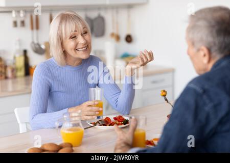 Lächelnde ältere Ehepartner genießen gemeinsam eine gesunde Mahlzeit Stockfoto
