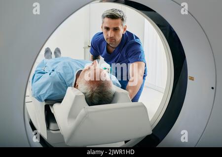 Älterer Mann beim CT-Scanner. CT-Scan-MTRA mit Blick auf den Patienten im Computertomographie-Scanner während der Vorbereitung auf das Verfahren Stockfoto