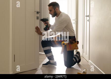 Portrait Junge männliche Tischler reparieren Türschloss Stockfoto