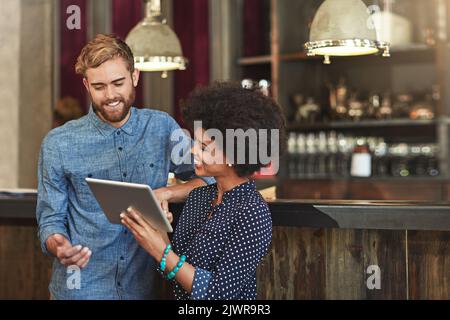 Ich denke, es ist an der Zeit, etwas Neues zu tun... junge Mitarbeiter in Cafés, die zusammen ein digitales Tablet nutzen. Stockfoto