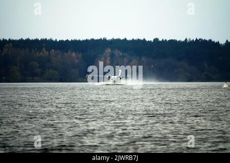 Das zweimotorige Wasserflugzeug ein Wasserflugzeug steigt aus dem Wasser, aus dem Waldsee, dem nördlichen Land auf. Wasserflugzeug Stockfoto