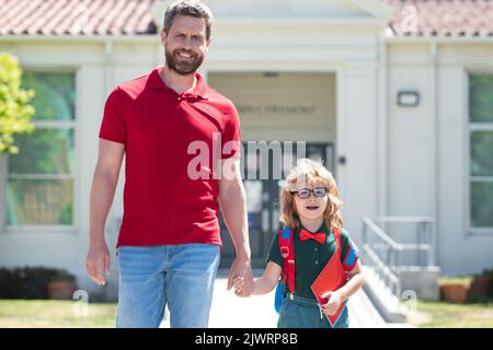 Vater unterstützt und motiviert Sohn. Kind geht zur Grundschule. Stockfoto