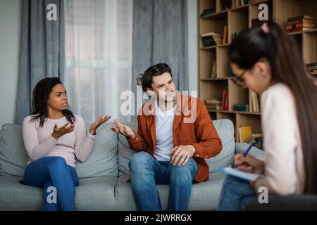 Beleidigt unzufrieden wütend emotionalen tausendjährigen verschiedenen Ehemann und Ehefrau schwören auf das Treffen mit Psychologen Stockfoto