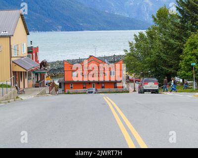 Haines Alaska USA - Juli 31 2008; orangefarbene Fassade am Ende der Straße mit doppelten gelben Linien und Bucht im Hintergrund Stockfoto