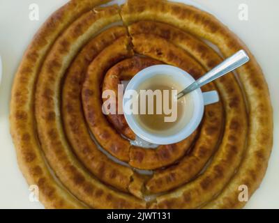 Tasse Kaffee mit Milch in der Mitte einer Runde Churros. Stockfoto