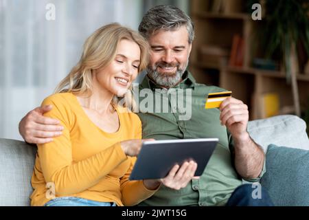 Paare Mittleren Alters, Die Online-Zahlungen Mit Digitalem Tablet Und Kreditkarte Vornehmen Stockfoto